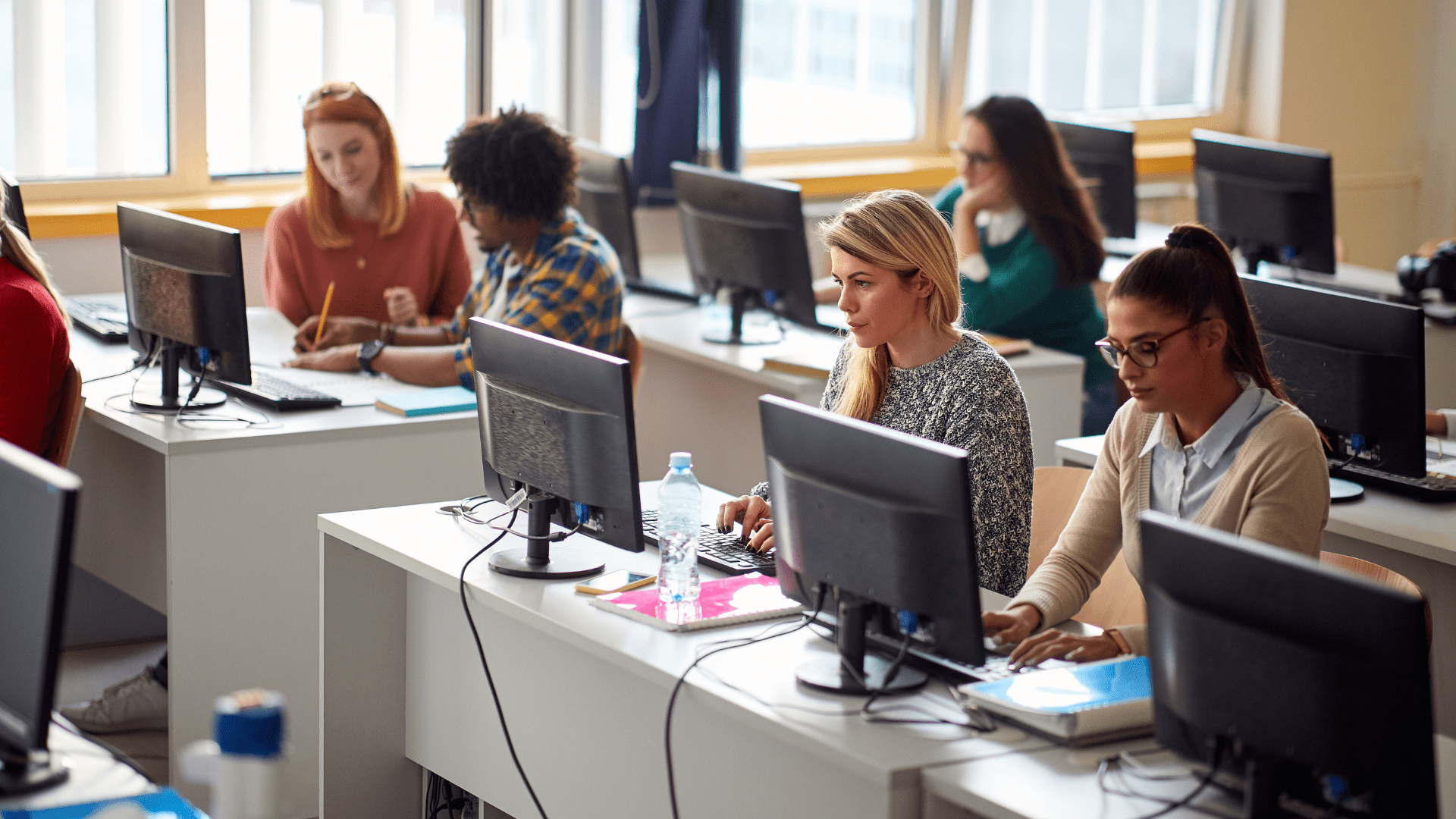 Une salle de formation avec plusieurs personnes travaillant sur des ordinateurs